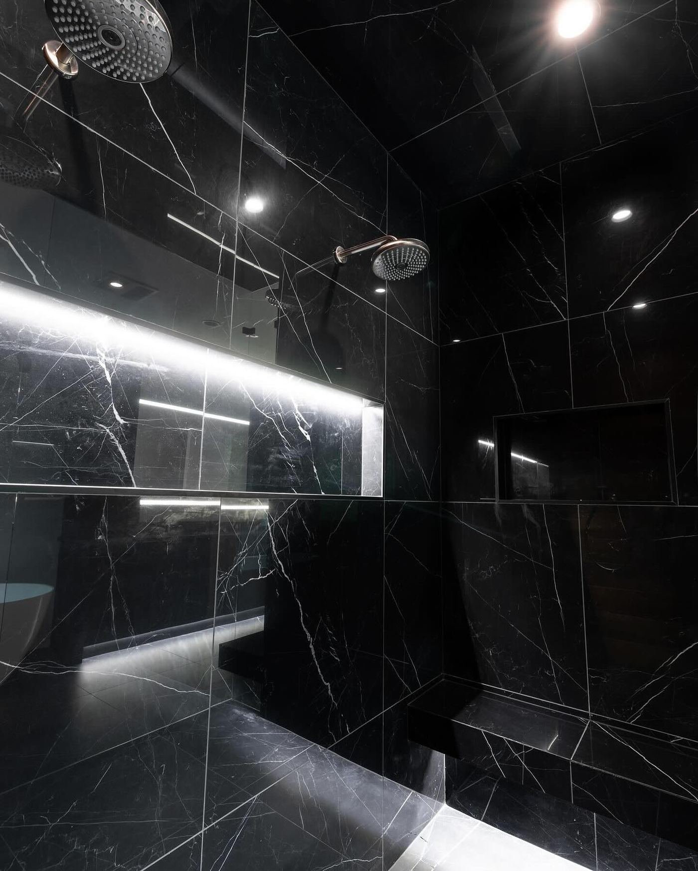 Black marble bathroom with backlit LED strip lighting and a ceiling-mounted rain shower