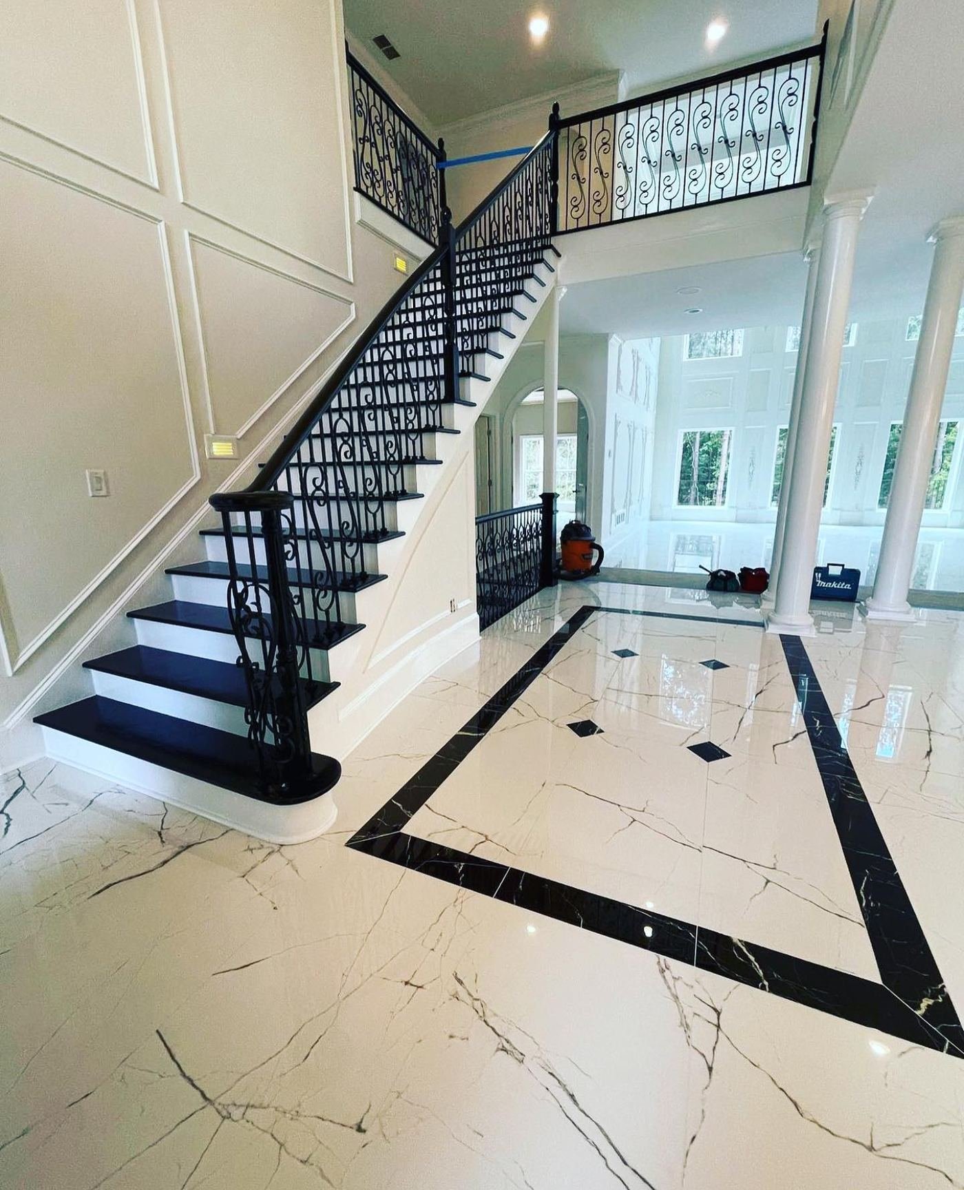Polished marble entry floor with a black stone inlay border beside a staircase